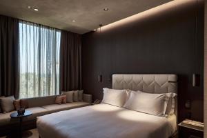 ミラノにあるHotel VIU Milan, a Member of Design Hotelsの大きなベッドとソファが備わるホテルルームです。