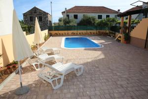 a patio with chairs and a pool and an umbrella at Apartmani Šprljan in Vodice