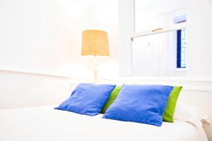 a white bed with blue and green pillows at Prado Museum Boutique in Madrid