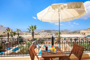 eine Terrasse mit einem Sonnenschirm, einem Tisch und Stühlen in der Unterkunft L'Ghorfa in Xagħra