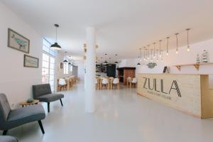 a lobby with chairs and tables and a restaurant at Zulla Nazaré`s Surf Village in Nazaré