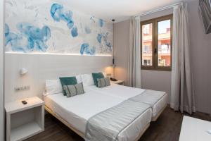 a bedroom with a white bed with a blue painting on the wall at Hostal Operaramblas in Barcelona