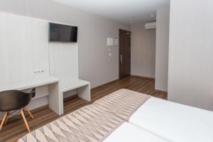 a bedroom with a bed and a desk and a television at Hostal Operaramblas in Barcelona