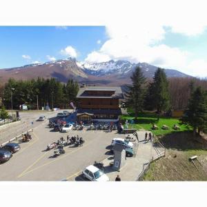 a parking lot with a building with cars and people at B&B Passo del Cerreto in Cerreto Laghi