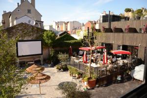 a patio with tables and umbrellas and a screen at MOB HOTEL Paris Les Puces in Saint-Ouen