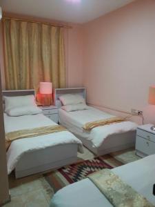 pokój z 3 łóżkami i lampką w obiekcie My Home Petra w mieście Wadi Musa