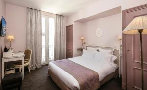 a hotel room with a bed and a desk and a window at Le Cavendish in Cannes