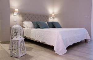 una camera da letto con un grande letto bianco con cuscini blu di Le Saline Suites a Carloforte