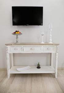 uma mesa de consola branca com uma televisão na parede em Le Saline Suites em Carloforte