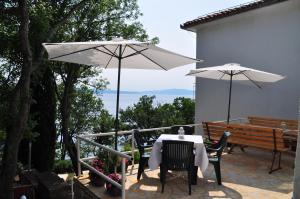 a patio with a table and two white umbrellas at Simple beachfront rooms Bego in Kraljevica