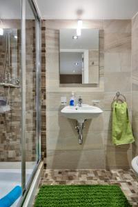 ein Badezimmer mit einem Waschbecken und einer Dusche mit einem grünen Teppich in der Unterkunft Borgo suites - self catering apartments - Valletta - By Tritoni Hotels in Valletta
