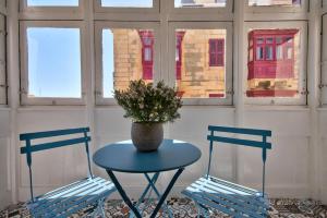 a table with a vase on it with two chairs at Borgo Apartments 1 & 2 Bedroom Self-Catering Units in Central Valletta in Valletta