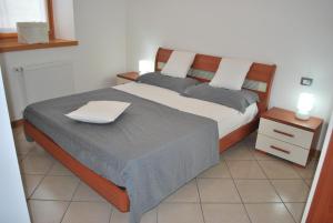 1 dormitorio con 1 cama y mesita de noche de color blanco en Cadari' Appartamenti, en Castel Condino