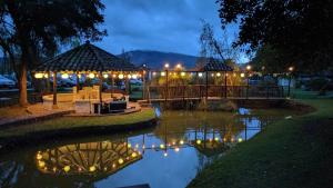 un cenador con luces junto a un río por la noche en Posada Cafe La Huerta en Guasca