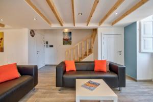 a living room with a black leather couch and orange pillows at Borgo Apartments 1 & 2 Bedroom Self-Catering Units in Central Valletta in Valletta