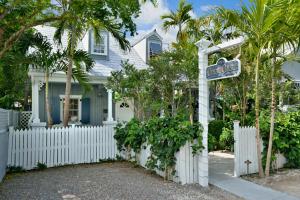 a house with a white fence and a street sign at Center Court-Boutique Old Town Lodging in Key West