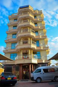 a tall yellow building with cars parked in front of it at Silver Paradise Hotel in Dar es Salaam