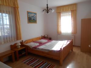 um quarto com uma cama de madeira e 2 janelas em Vendégmarasztaló Porta em Szalafő
