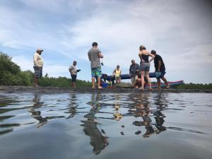 een groep mensen die op de oever van een waterlichaam staan bij Puerto Barillas in Bahia de Jiquilisco