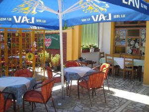 un restaurante con mesas y sillas bajo una sombrilla azul en Motel Sretno Good Luck, en Trnovo
