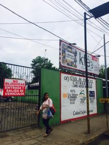 a woman standing on a sidewalk next to signs at Hotel Plaza Cosiguina in Chinandega