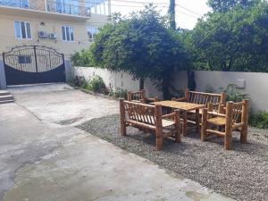 two wooden benches and a table in front of a building at Guesthouse Natali in Gonio