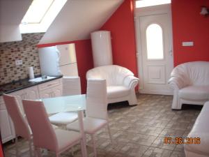 uma cozinha com cadeiras brancas, uma mesa e um frigorífico em Kelemen Apartmanok em Abádszalók