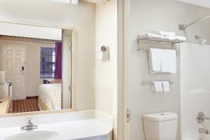 a bathroom with a sink and a toilet and a mirror at Days Inn by Wyndham Lexington in Lexington