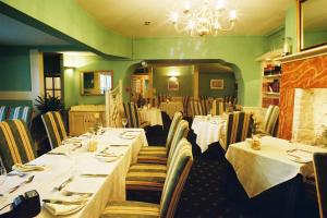 a dining room with tables and chairs and a chandelier at Bishopsgate House Hotel in Beaumaris