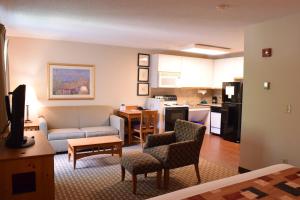 a living room with a couch and a kitchen at Cresthill Suites Syracuse in East Syracuse