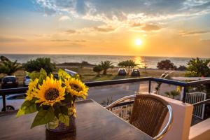 un vase de tournesols assis sur une table sur un balcon dans l'établissement Faros Apartments, à Mitikas