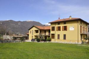 uma grande casa amarela com um campo verde em frente em il coniglio sulla luna em Erba