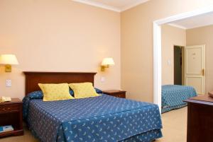 1 dormitorio con 1 cama con sábanas azules y almohadas amarillas en Provincial Plaza Hotel en Salta