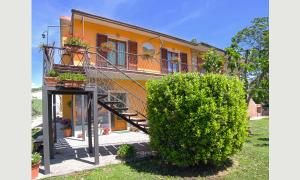 una casa amarilla con una escalera y un arbusto en Agriturismo La Valle degli Ulivi, en Semproniano