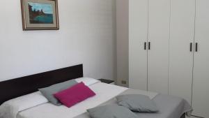 Bagnolo del SalentoにあるTenuta Schiauddiのベッドルーム(ピンクの枕と白いベッド付)