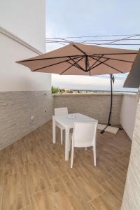 une table et des chaises blanches sous un grand parasol dans l'établissement Rifugio Massafera 2, à Massafra