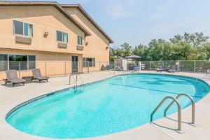 a swimming pool with chairs and a building at Super 8 by Wyndham Redding in Redding