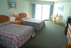 een hotelkamer met 2 bedden en een tafel bij North Shore Inn in Port Hardy