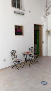 eine Terrasse mit 3 Stühlen, einem Tisch und einem Tisch in der Unterkunft Alla corte della suocera in Bari