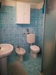uma casa de banho em azulejos azuis com um WC e um lavatório em Villa Caterina em Mondello