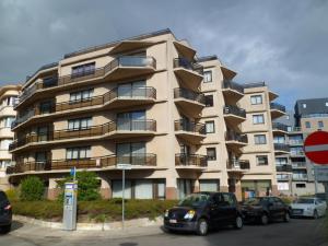 a large apartment building with cars parked in front of it at Appartement Residentie Amadeus met garage-lift in Sint-Idesbald