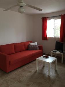 Una sala de estar con un sofá rojo y una mesa. en Casita Blanca Bayahibe, en Bayahibe