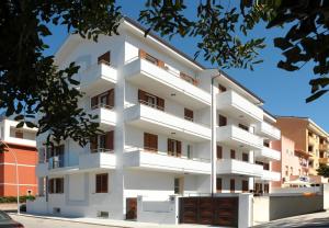 a white apartment building with balconies on a street at Alkira Lodge in Alghero