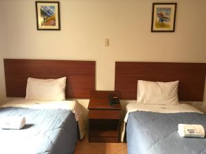 a hotel room with two beds and a table at Hostal Bond in Huaraz