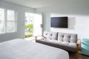 a bedroom with a couch and a flat screen tv at The Shore House in Narragansett