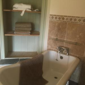 a bathroom with a tub and a shelf with towels at Château Ville Voisin in Augan