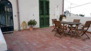 een patio met een tafel en stoelen en een groene deur bij Appartamento di Villa Ellizabeth in Milazzo