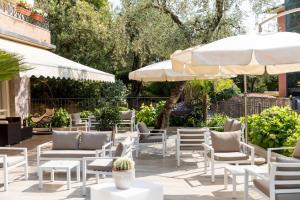 eine Terrasse mit weißen Stühlen und Sonnenschirmen in der Unterkunft Hotel Pace in Torri del Benaco