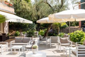 a patio with white chairs and umbrellas at Hotel Pace in Torri del Benaco
