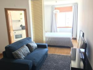 uma sala de estar com um sofá azul e uma cama em 8-bit-building em Lisboa